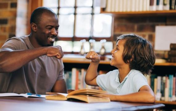 Teacher and student giving each other a high five in a library