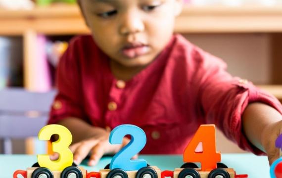 Little boy playing with mathematics wooden toy at child care
