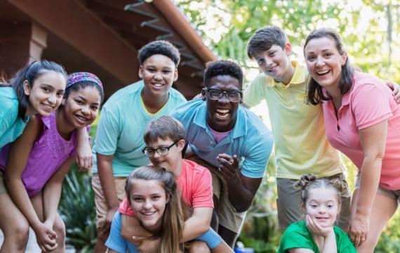 Group of teens and camp staff smiling together outdoors at camp