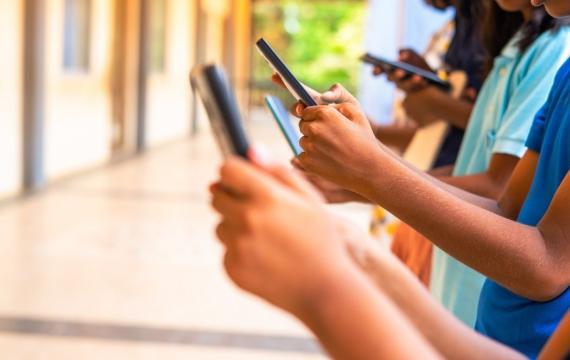 group of children hands busy using smartphone at school corridor