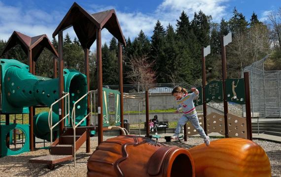 girl jumping across climbers at Shoreview Park's baseball playground