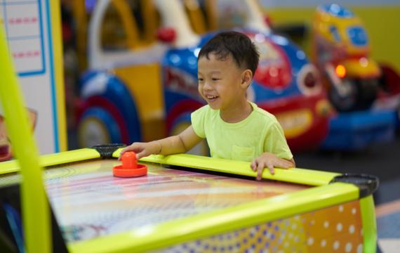 little boy playing air hockey at an arcade