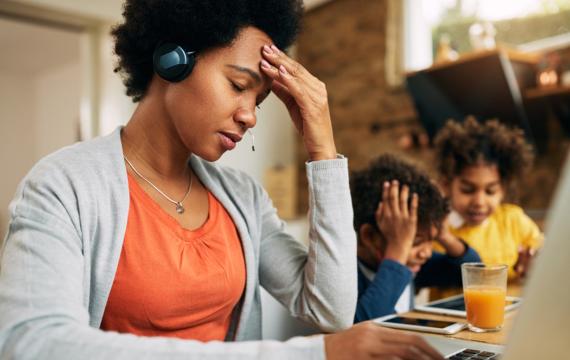 overcommitted mom looking stressed out with kids in the background