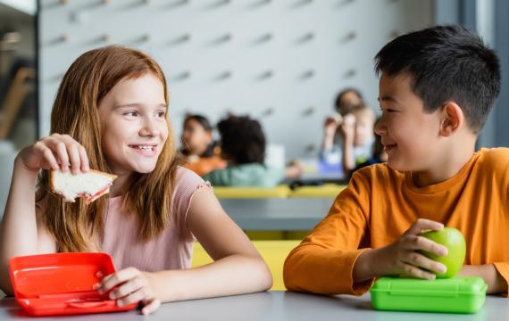 two kids eating lunch together at school