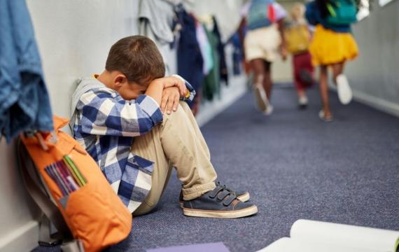 little boy sitting in corridor anxious at end of school 