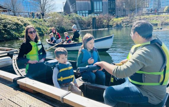 family of four rowing in a rowboat on South Lake Union in Seattle at The Center for Wooden Boats