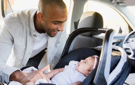 dad and girl in a car seat smiling at each other