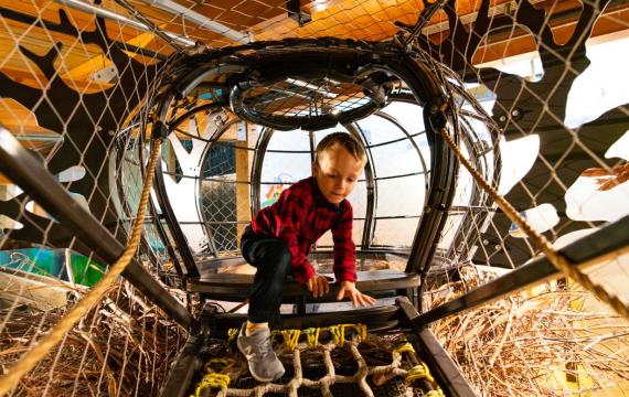 young child climbing in a rope climber at Hands on Children's Museum, which is hosting spring break activities this weekend