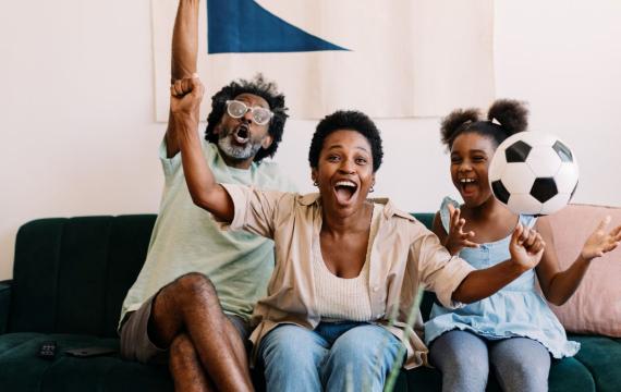 A family excitedly cheers while watching a FIFA World Cup soccer game