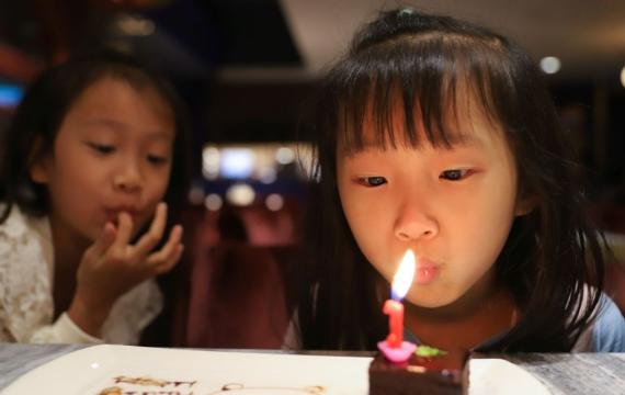 little girl blowing a birthday candle