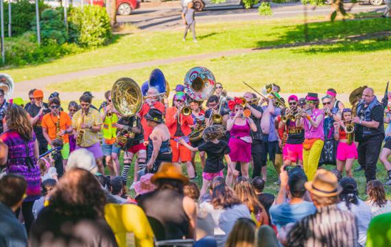 crowd watching a marching bad with big instruments play during Honk Fest West in Seattle