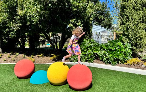 young girl hopping across bright play structure at a new playground opening this weekend in Seattle