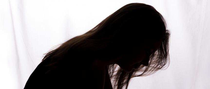 silhouette of a woman bent forward with hair falling across her face