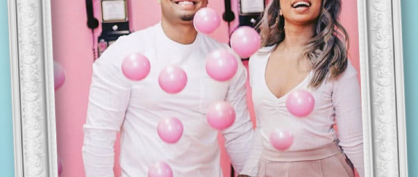 Man and woman taking a selfie with pink balloons in front of them 