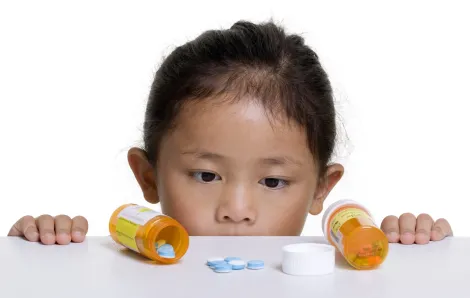 Kid looking at bottle of pills