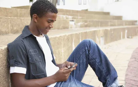 Teen boy typing on cell phone