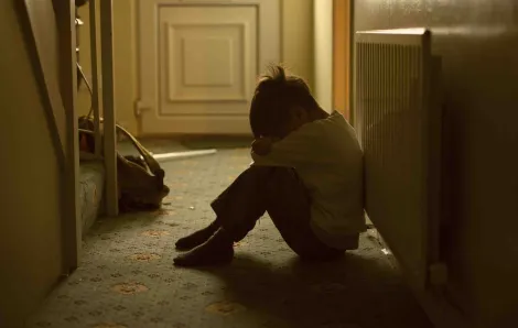 Upset child sitting in dark hallway
