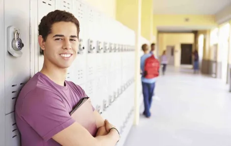 High school male student leaning against locker