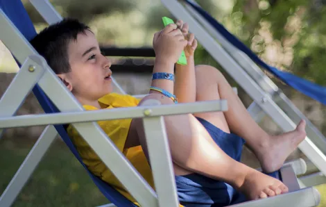 Boy outside with phone in lawn chair