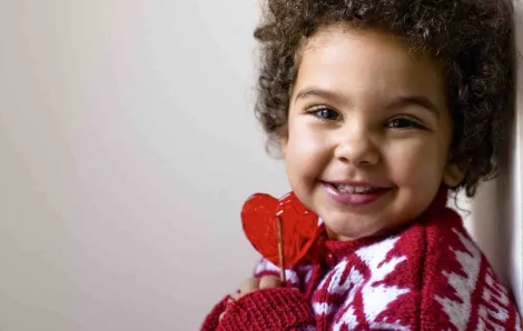 Valentine's Day kid holding heart-shaped lollipop