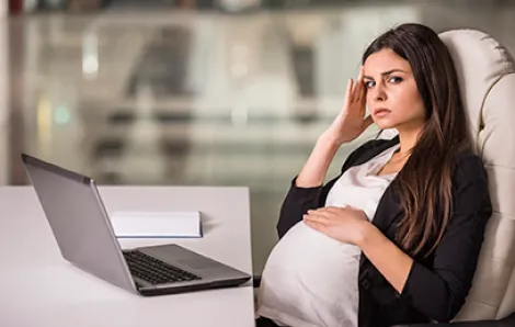 Frustrated pregnant woman at computer