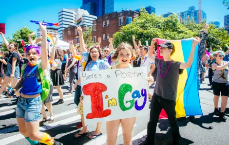 A kid of about 12 years old holds a sign that says I'm Gay during a Seattle Pride event