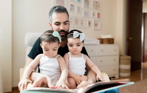 father reading to twin daughters