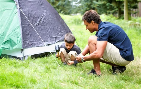 Father and son setting up tent for last-minute camping