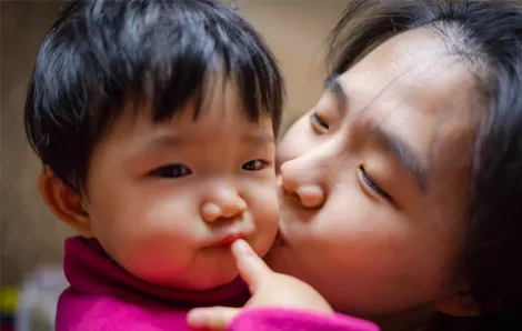 Mom kissing child's cheek