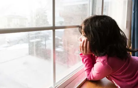 girl looking out the window at snow