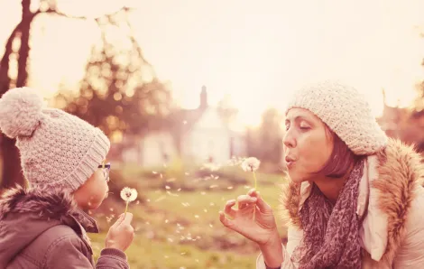 Mom and daughter blowing dandelion seeds