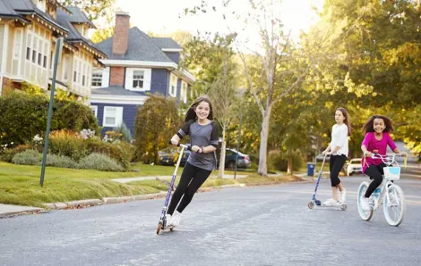 free range girls riding scooters through the neighborhood