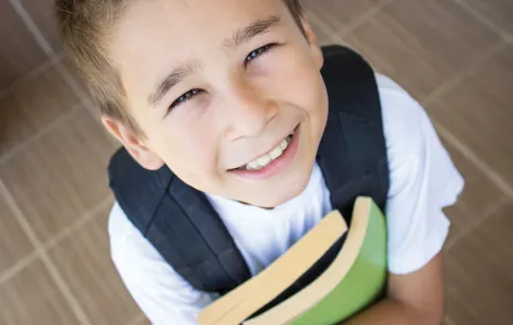 boy holding books and smiling
