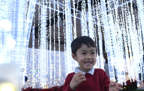 little boy smiling with glittering lights behind him