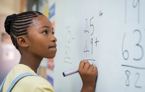 middle school girl doing math on a whiteboard