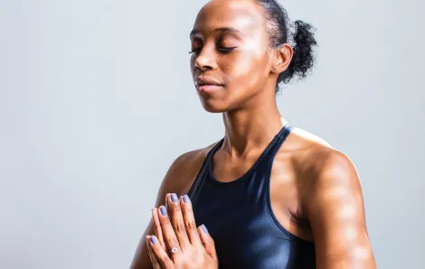 woman meditating with hands together and eyes closed