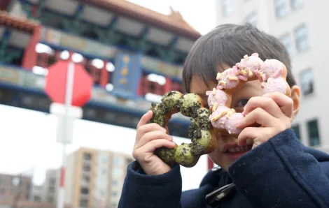 kid holding dochi mochi doughnuts up to his face best eats with kids in seattle's chinatown international district