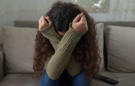 teen girl sitting on the couch with her head in her arms
