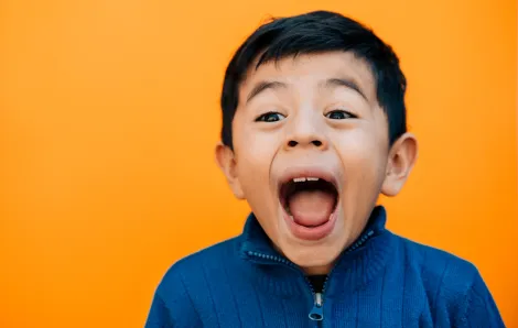 surprised happy little boy with a bright orange background