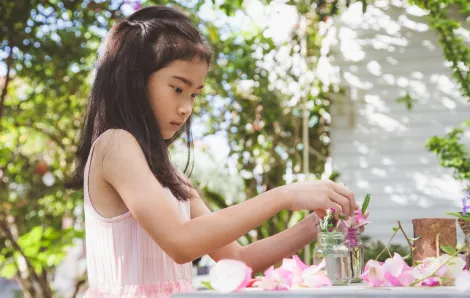 little girl playing with pink flowers