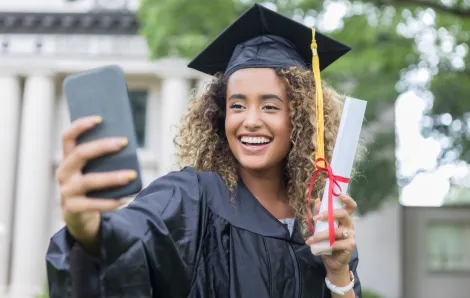 girl in a cap and gown taking a selfie alone