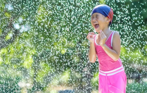 Girl running through the sprinkler, water play activity for summer