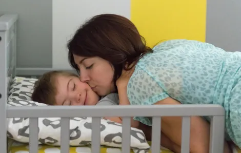 mother kissing her child with down syndrome at naptime