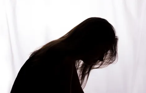 silhouette of a woman bent forward with hair falling across her face