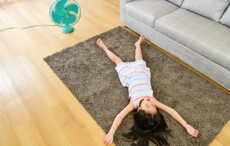 little girl lying on the floor in front of a fan