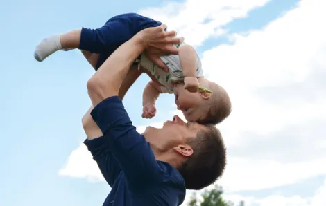Father holding up his baby with their foreheads together smiling