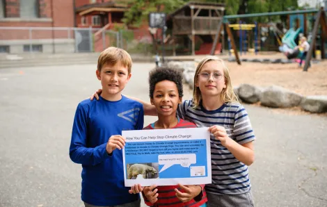 3 giddens students holding a climate change poster