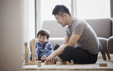 father and son playing with wood blocks on the living room floor