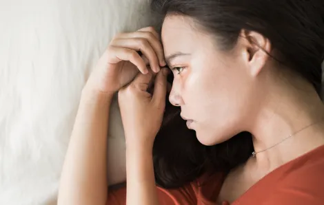 closeup of a young woman lying on her side staring forward looking depressed