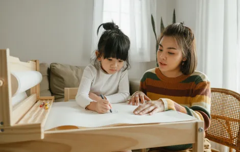 mother and daughter drawing at a child-size table together